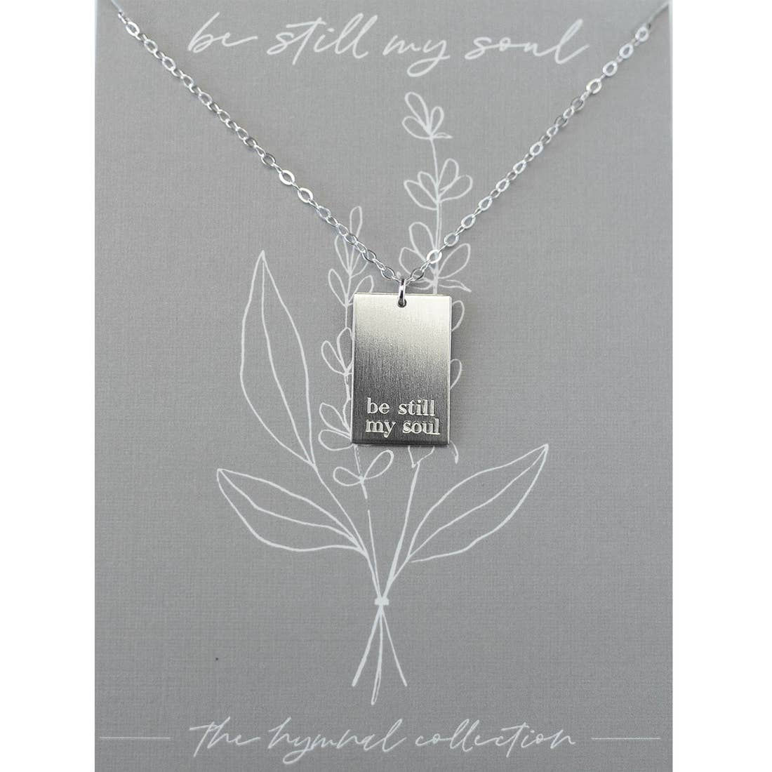 Silver necklace with engraving: 'be still my soul' on botanical grey card.