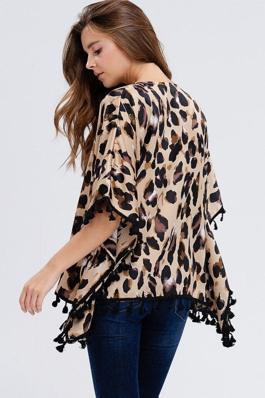Thumbnail: Woman wearing animal print kimono with black tassels and denim jeans