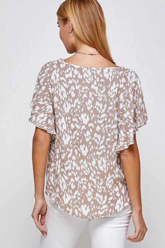 Thumbnail: Woman wearing beige top with white leopard print; elegant fashion style.