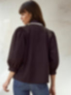 Woman wearing a black blouse with puff sleeves and visible white trim. Black Bow Blouse.