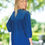 Thumbnail: Smiling blonde woman looking over shoulder wearing a blue dress outside.