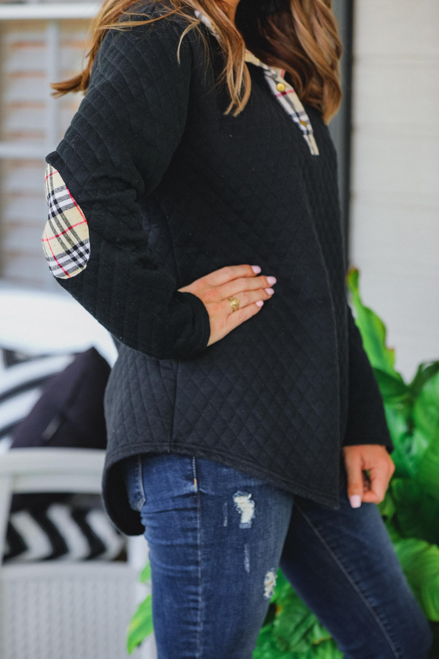 Woman wearing black quilted top with elbow patch and jeans