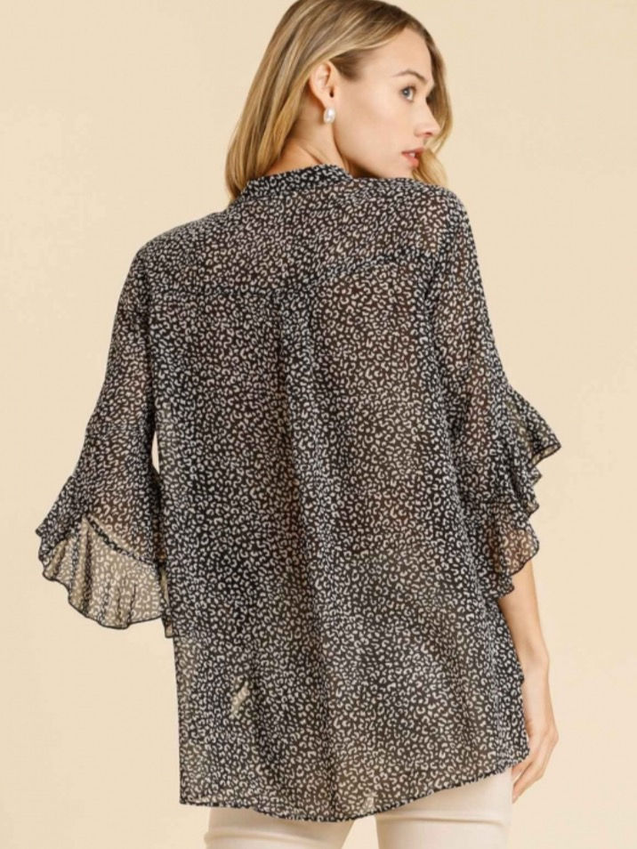 Thumbnail: Woman wearing a black and white patterned top with ruffle sleeves