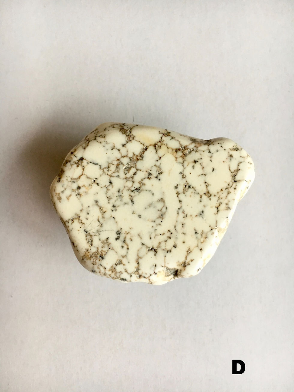 Thumbnail: Close-up of a white stone with brown veins on a white surface.