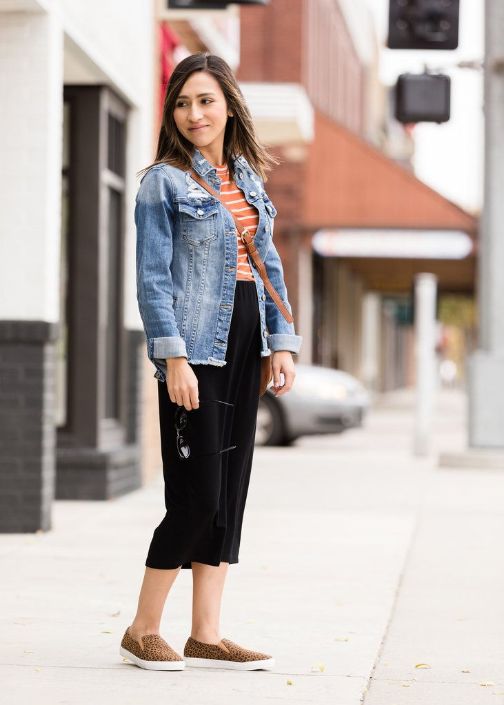 Thumbnail: Woman wearing denim jacket and black pants, walking on the sidewalk
