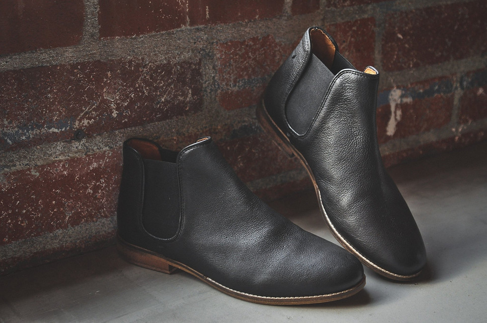 Black leather boots leaning against a brick wall background My Site 1