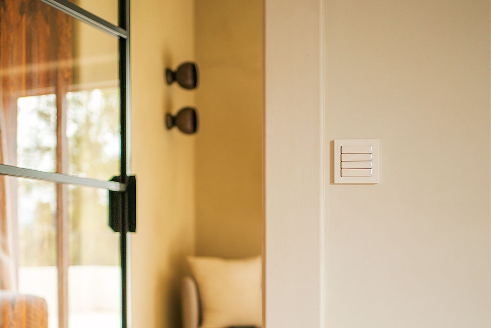 Light switch on beige wall next to sliding glass door. Soft lighting, cozy setting with a blurred view of an outside area.