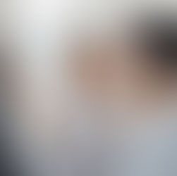 Woman adjusting smart home control panel while man watches smiling. Screen displays temperature 23°C. Modern, bright indoor setting.