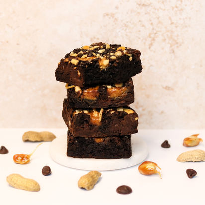 Stack of brownies, candied peanuts, and chocolate chips. 
