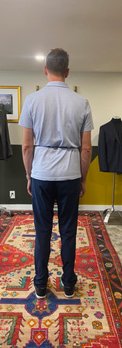 Client seen from the back during posture evaluation at Allan David Bespoke, highlighting a dropped right shoulder—an asymmetry commonly addressed through bespoke tailoring.