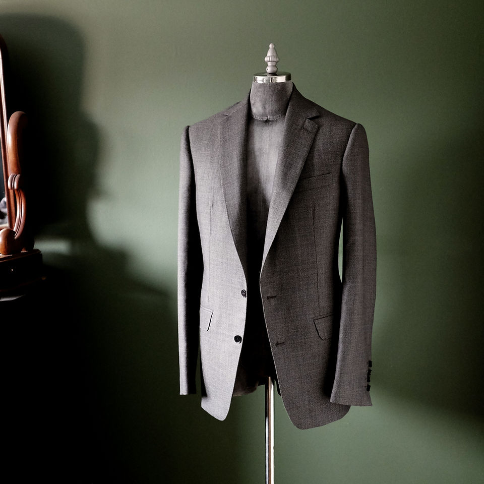 Mid-grey bespoke wool jacket on mannequin, showcasing lightly roped shoulders and minimalistic design.