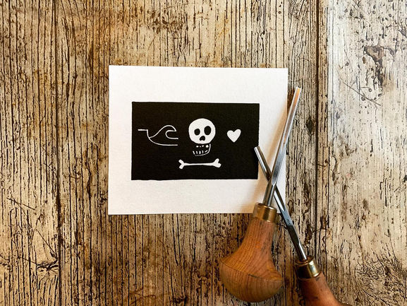 Mini linocut print depicting a pirate flag.