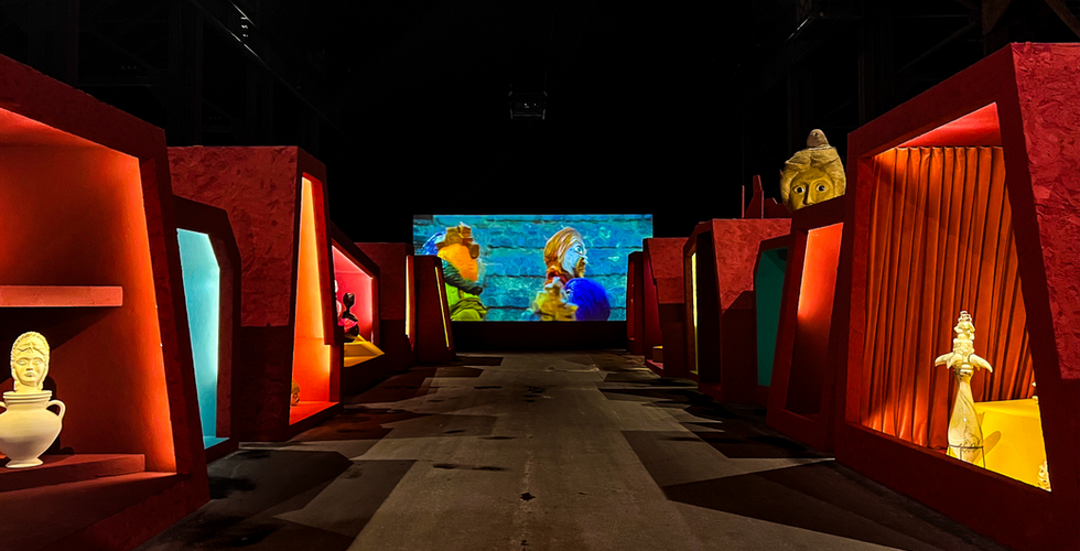 Vue de l’installation « Je suis les hymnes des nouveaux temples » de Wael Shawky à la Fondation LUMA à Arles, présentant un espace qui associe projections, éclairages et sculptures dans La Grande Halle.