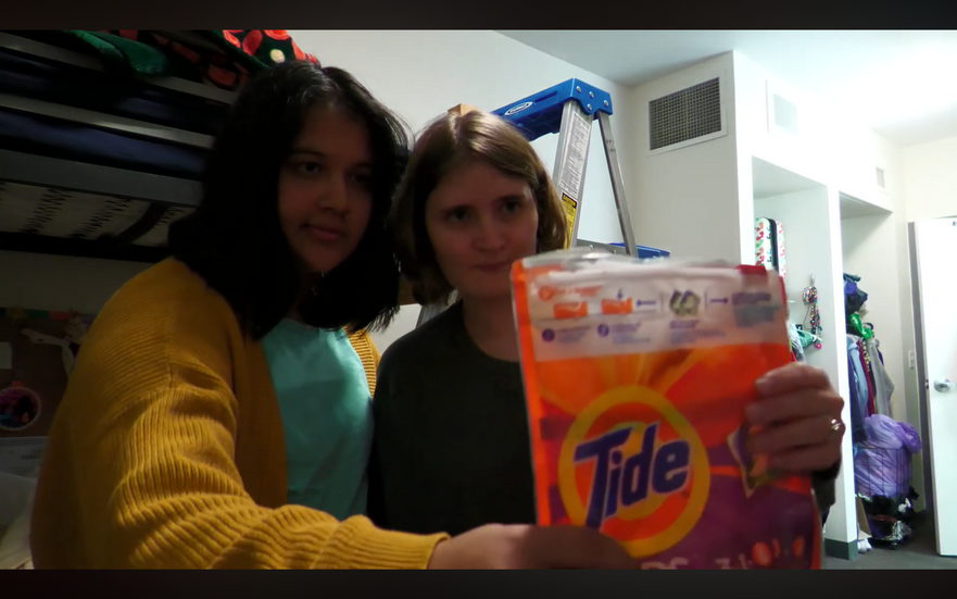 Two women holding a bag of Tide Pods.