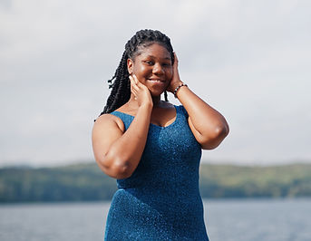 A person in a blue sleeveless top stands outdoors near water, covering their face with their hands, possibly reflecting on a bariatric surgery evaluation.