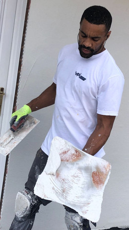 man in white t shirt with plastering tools in hands