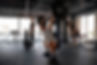 Man performing barbell back squat, two others exercising nearby