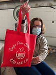 Volunteer who is assembling PPE supply kits for teachers holds up a kit bag that reads Cape Fear OSMS Red 4 Ed.