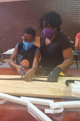 A child and adult cut elastic for face shields which are being assembled by volunteers to keep folks safe from COVID-19.