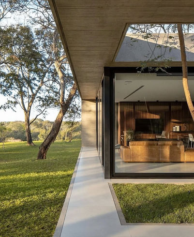 Modern home exterior with large glass windows and green lawn Broome Construction