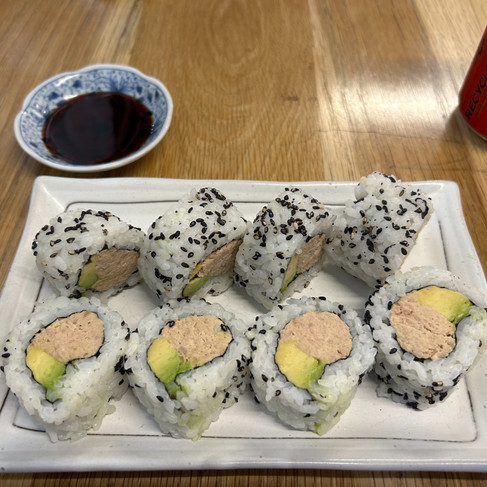 Tuna and avocado sushi roll with a small plate of soy sauce.