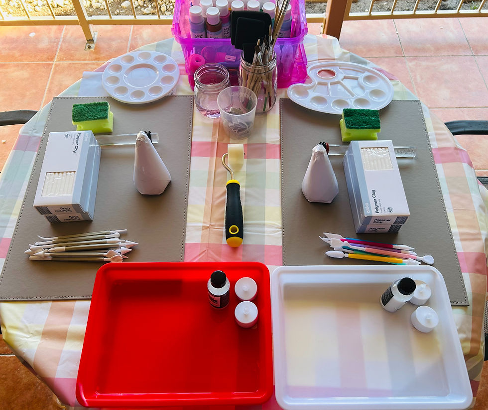 Art supplies on a checkered table: paint, brushes, palettes, sponges, and rollers. Red and white trays hold paint bottles, creating a creative vibe.