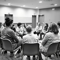 black & white Young people focus group in hall sitting in circle on chairs mentor speaking