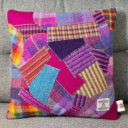 Patchwork pink cushion sitting upright on a grey couch.