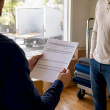 Hands holding generic insurance certificate near moving supplies