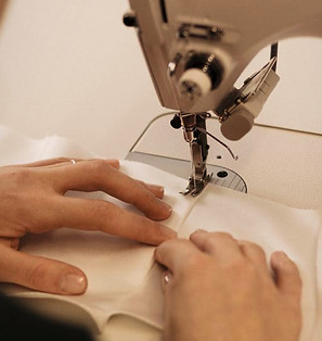 Mãos costurando tecido em máquina de costura