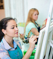 Person painting at an easel in a group setting