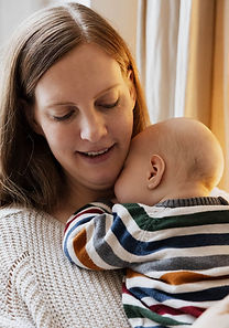 Mama mit Baby im Arm am Fenster – Coaching für Mütter für mehr Ruhe im Alltag