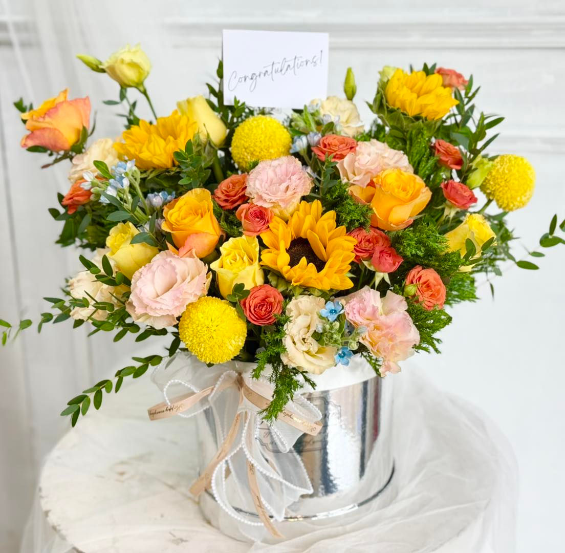 Vibrant flower box with sunflowers, roses, lisianthus, and chrysanthemums.