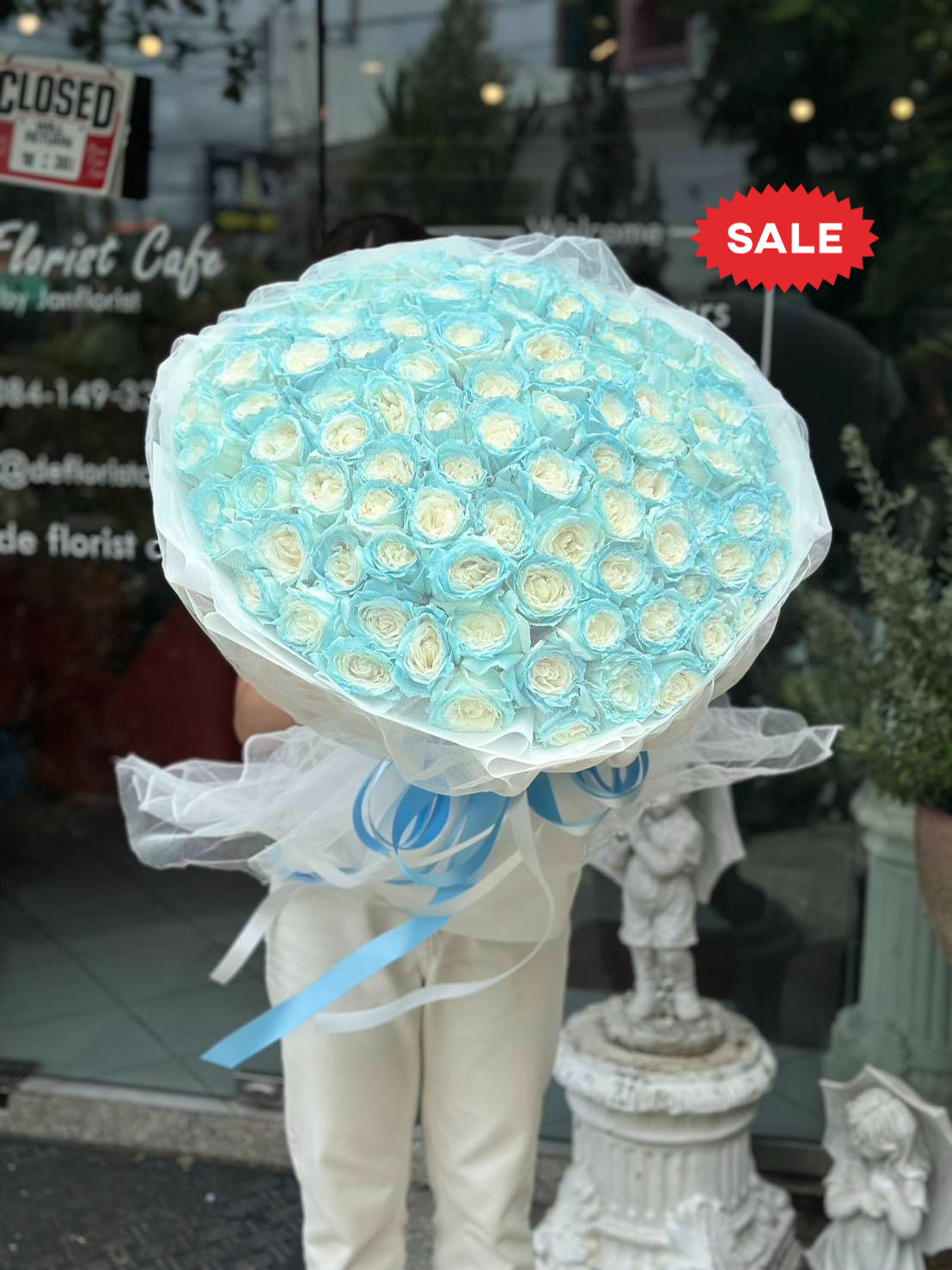 Bouquet of white roses with pastel blue spray paint, wrapped with white and blue ribbons