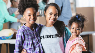 Volunteer hugging two girls