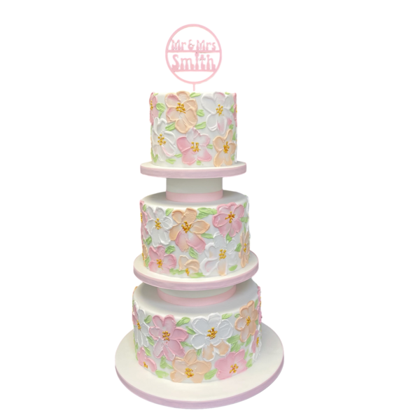 Four-tier wedding cake with pastel sugar paste flowers and pink trim.