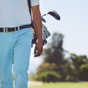 Man carrying golf bag on a sunny golf course