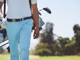 Man carrying golf bag on a sunny golf course