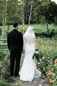 Bride and groom walking through the garden of zinnias.