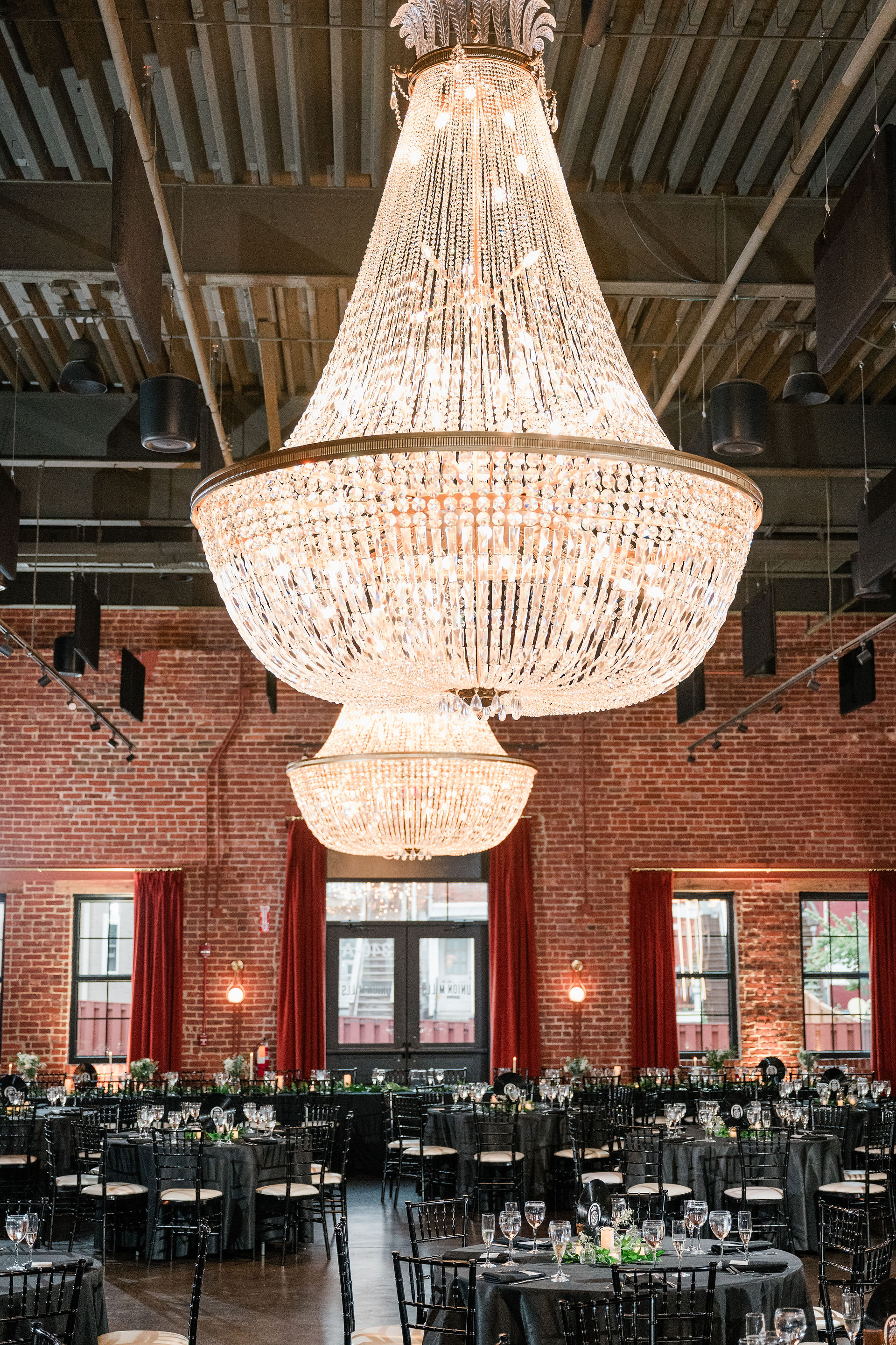 wedding reception tables set up under chandeliers 