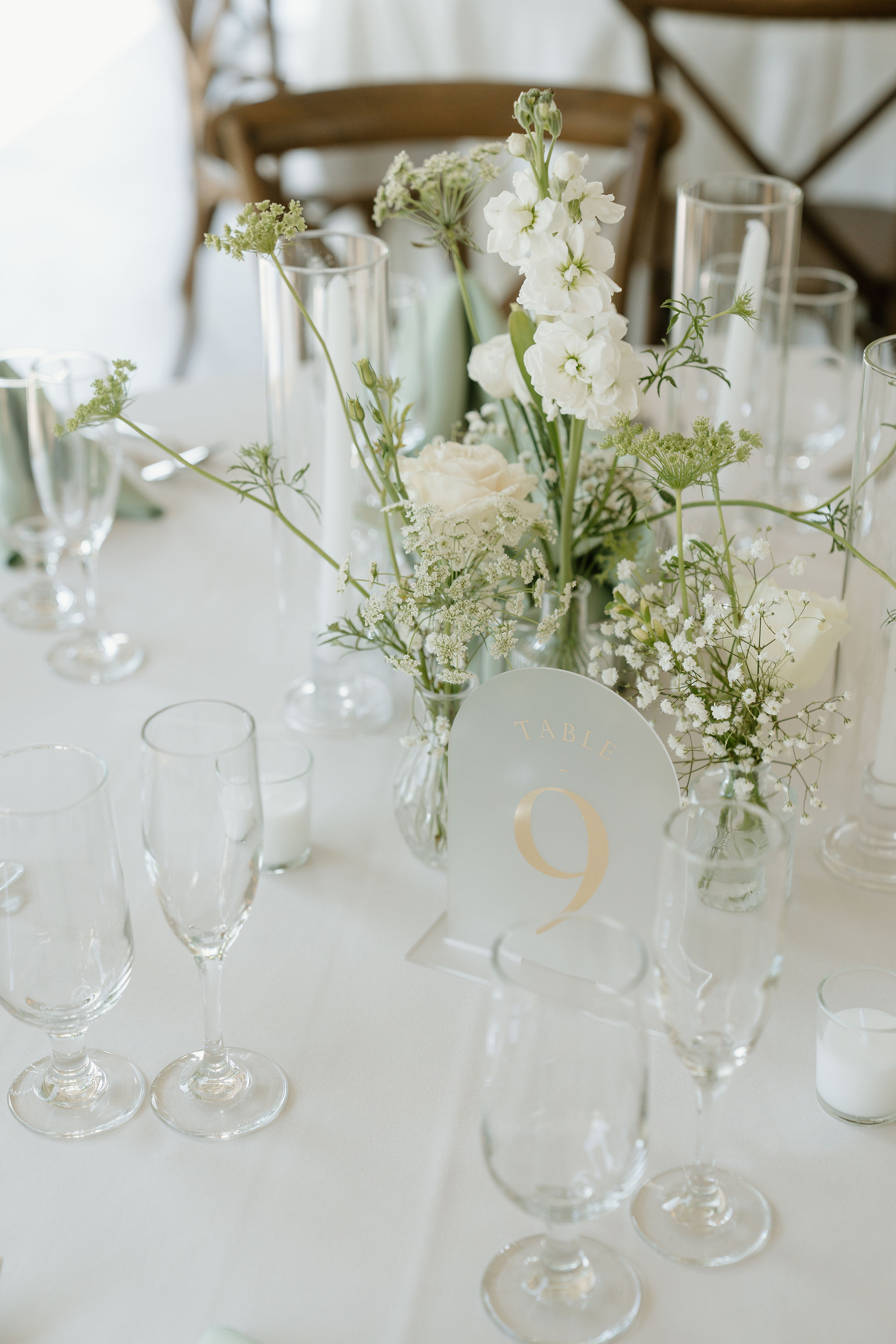 A centerpiece at a table with a white linen and bud vases with white flowers at Glen Ellen