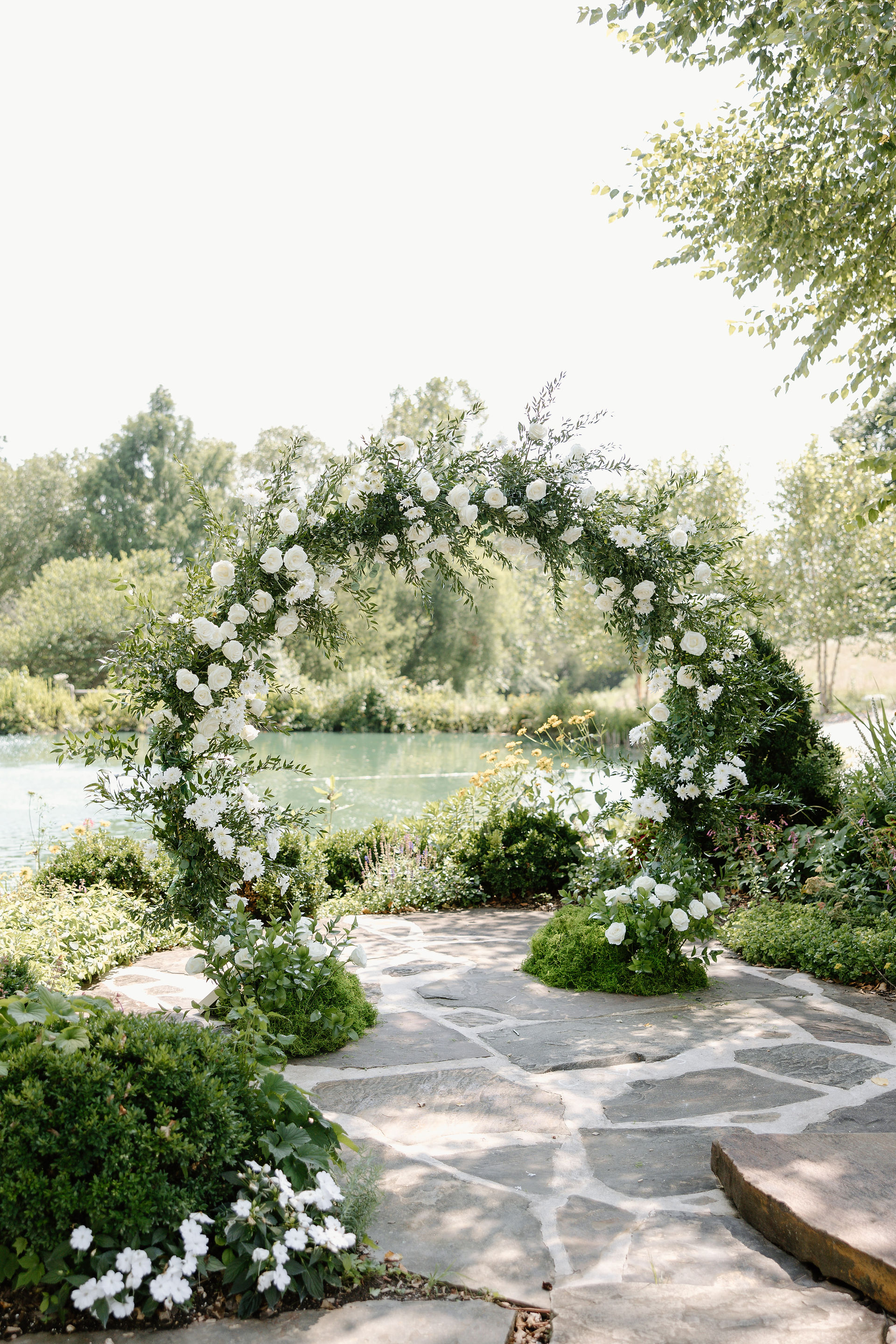 A white floral arch in front of the pond at Glen Ellen