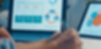 Laptop screen with survey results: charts and text highlighted in blue, orange, and green. Blurred hand writing. Professional setting.