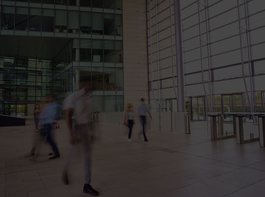 Blurred people walking through a modern glass office lobby.