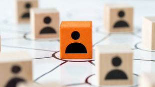Orange cube with a person icon at the center of wooden cubes connected by lines on a white background, symbolizing a network.