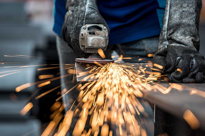 Industrial worker cutting metal with many sharp sparks