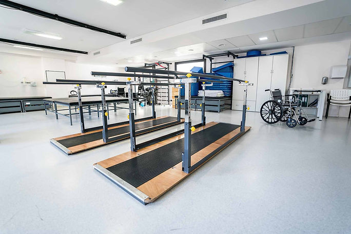 Empty room at a physical recovery clinic with parallel bars and materials.jpg