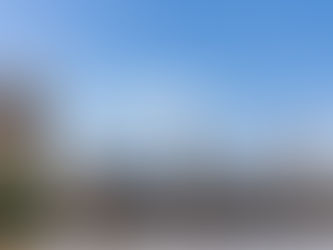 The Palace of Westminster from across the River Thames. There is a blue sky in the background and some fluffy white clouds.