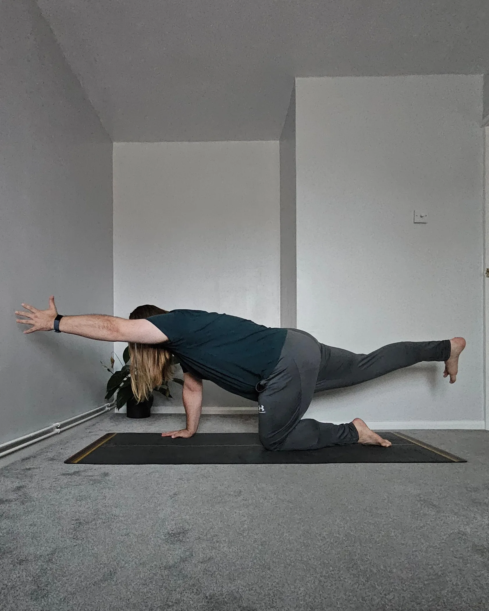Sam Turner Yoga is in a tabletop position. His left arm is extended forward. His right leg is extended backwards.