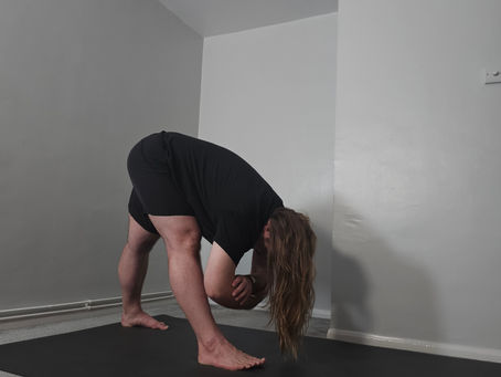 Sam in pyramid pose, folding over the front leg with both legs straight, forearms suspended in the air.
